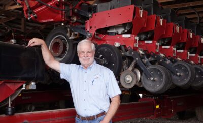 Willie German, farmer, leans on farm equipment